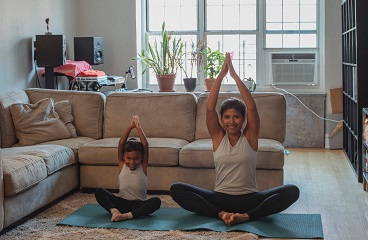 happy-mother-and-daughter-stretching-together-at-home